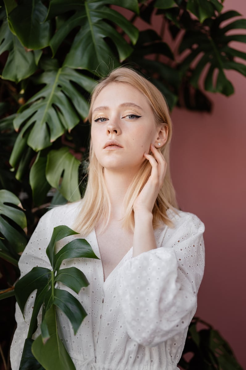 Woman in White Dress Standing Beside Green Plant